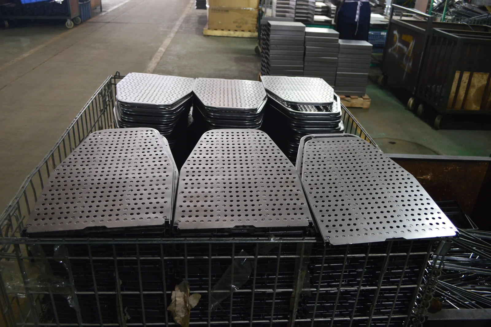 Pilas de paneles metálicos perforados para tablas de planchar en una zona de trabajo de la fábrica